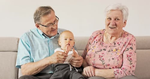 Senior Couple and Baby Sitting on Couch