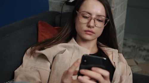 Woman Relaxing on Couch Using Smartphone