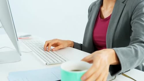 Femme d'affaires prenant un café tout en travaillant au bureau