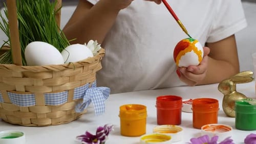 Happy Easter. Children drawing on painted eggs at the table, at home. Preparing for Easter holiday.