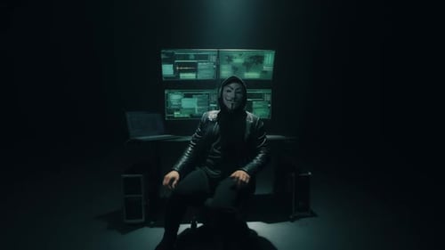 Anonymous Hacker Wearing Mask Sits in Dark Room