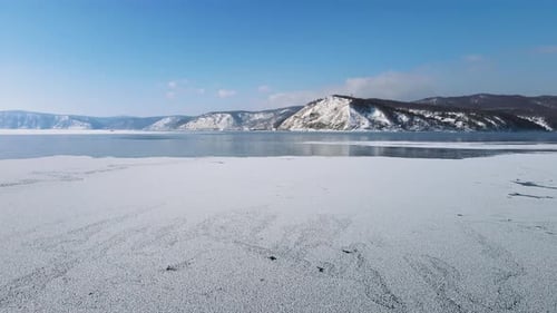 A cinematic winter landscape on sunny clear day. Open water near thin spring ice