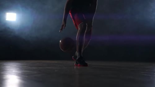 Un jeune homme adulte, ballon de dribble de joueur de basket-ball, terrain de basket intérieur sombre