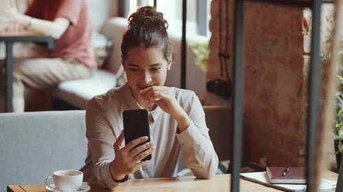 Cheerful Businesswoman Video Calling on Smartphone in Cafe