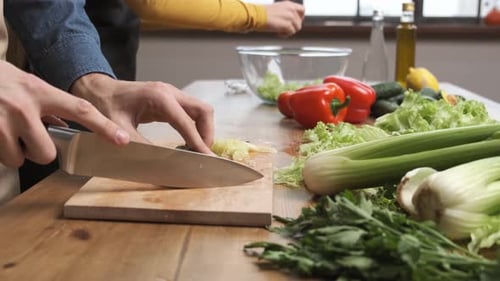 Person Slicing Cucumber for Salad Preparation