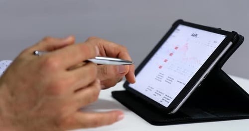 Man Analyzing Financial Data on Tablet with Stylus