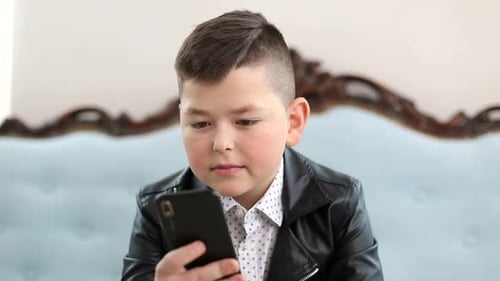 Boy Using a Phone and Smiling Indoors