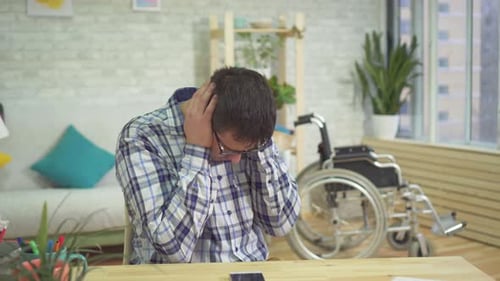Man Sitting at Table with Head in Hands