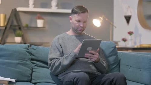 Man Relaxing on Couch Using Tablet at Home