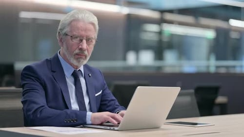 Mature Man Using Laptop in Modern Office