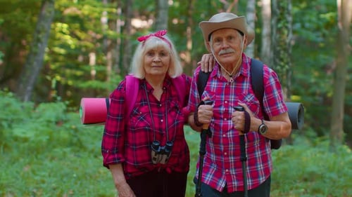 Smiling Senior Couple Hiking Together in Green Forest