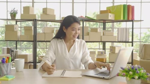 Woman Working at Desk with Laptop and Notebook
