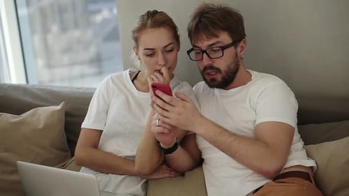 Couple Relaxing on Couch Looking at Phone