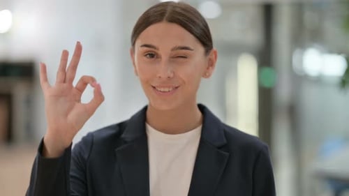 Smiling Woman Gives OK Sign in Corporate Office