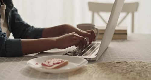 Woman Using Laptop at Table with Toast