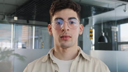 Closeup Caucasian Serious Puzzled Clever Guy Student in Glasses Looking at Camera Posing Indoors