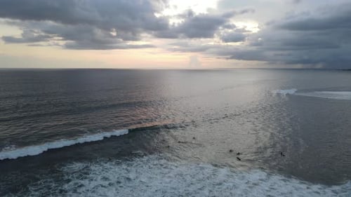 Aerial view of people surfing on waves during sunset when vacation in Bali, Indonesia.