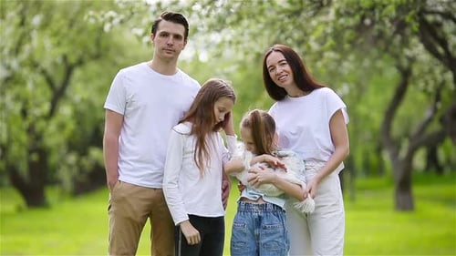Adorable Family in Blooming Cherry Garden on Beautiful Spring Day