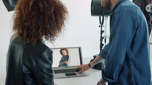 Photographer Showing Photos To Mixed Race Model Using Laptop Computer in Studio
