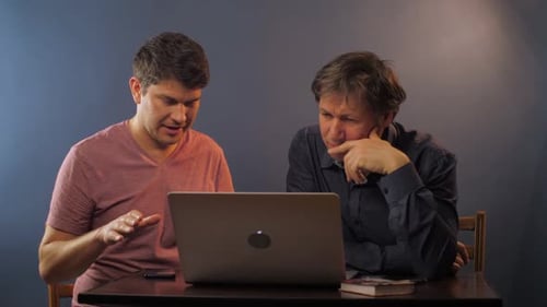 Un homme explique comment travailler avec un nouveau programme à un collègue senior