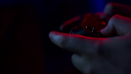 Hands Using Video Game Controller in Red and Blue Light