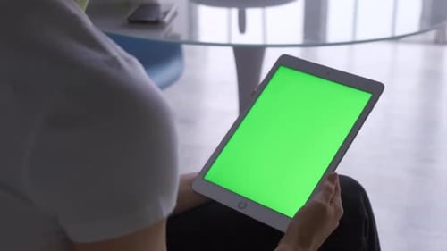Woman sitting on the floor and using vertical tablet computer with green screen