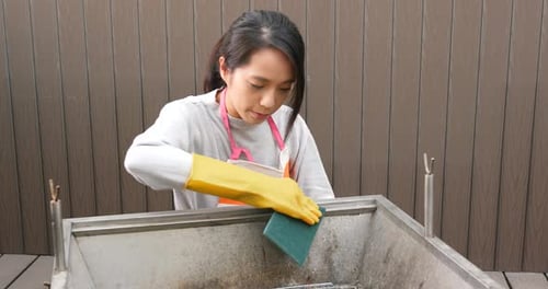 Woman Cleans Barbeque Pit with Scrubbing Sponge