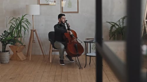 Young Adult Plays Cello in Light Airy Room