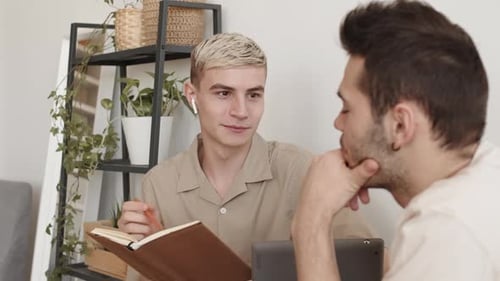 Deux hommes assis à une table à l'intérieur et discutant