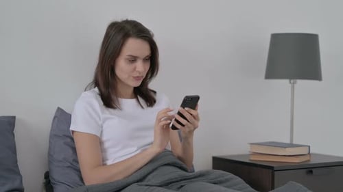 Woman Using Phone While Sitting in Bed