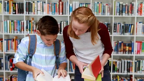 Smiling students reading book in library