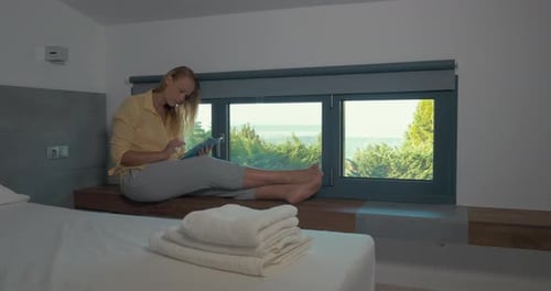 Woman using pad by the window in hotel
