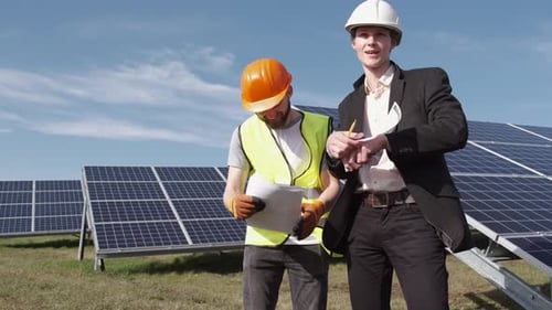 The Businessman and Worker Are Discussing Documents Standing Near Solar Batteries Outside