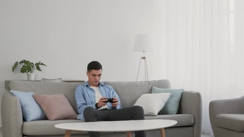 Man Playing Video Game on Couch at Home