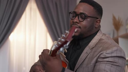 Man Plays Guitar and Sings Indoors