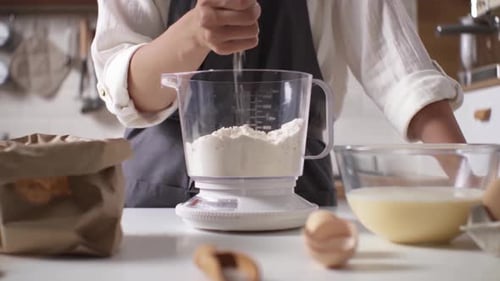Adding Flour to Mixing Bowl in Kitchen