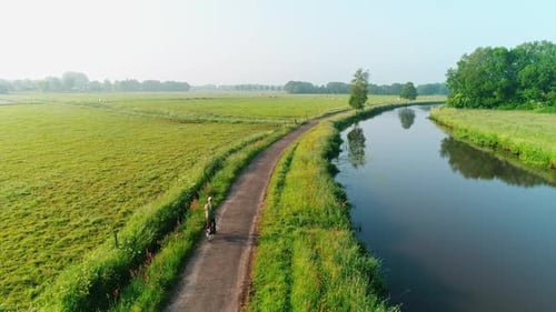 Rural Landscape Biker Riding Along Peaceful Canal Path