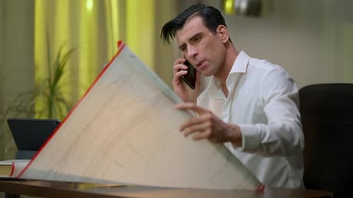 Architecte professionnel confiant du Moyen-Orient parlant sur smartphone pour analyser un plan architectural