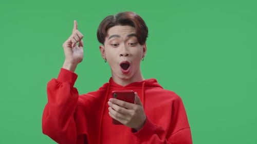 Young Asian Transgender Male Use Mobile Phone And Thinking About Something On Green Screen Studio
