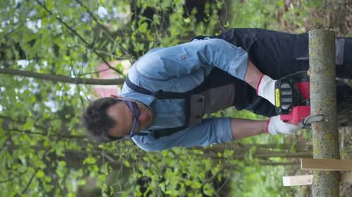 Man Cuts Tree Branch with a Chainsaw