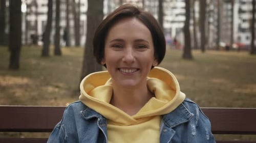 Woman Smiling Sitting on Park Bench on Sunny Day