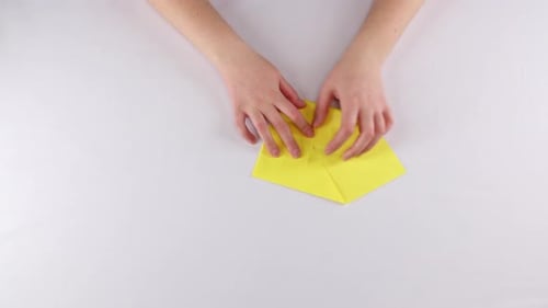 Hands Folding Yellow Origami Paper Art on White