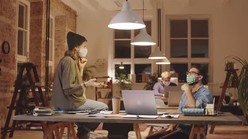 Male and Female Coworkers in Masks Discussing Job in Loft Office
