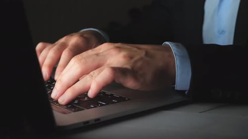 Male Hands of Manager Typing Text on Laptop Keyboard Late at Night