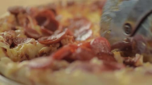 Cutting pepperoni pizza with pizza wheel close up shot