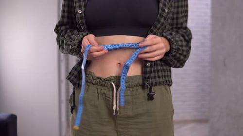 Woman Measures Waist with Blue Measuring Tape