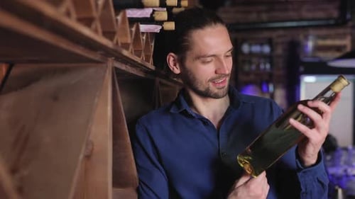 Smiling Man Holding Bottle of Wine in Wine Shop
