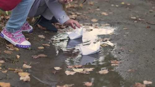 Children Play With Paper Boats in Puddle