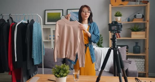 Woman Presents Clothing to Camera in Living Room