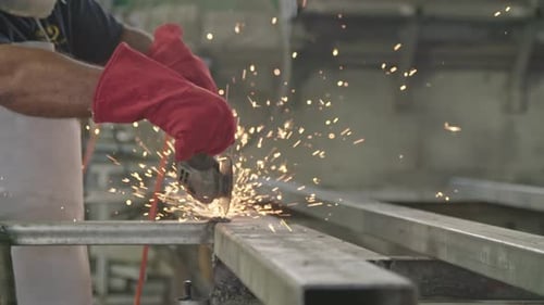 Cámara lenta de un trabajador que usa una amoladora de metal con chispas volando en un taller de metal